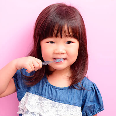 A toddler brushes her teeth