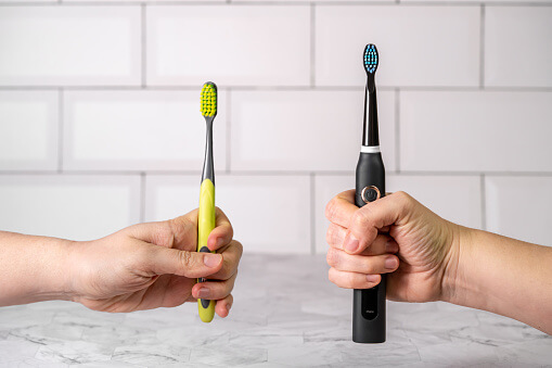 two people holding toothbrushes