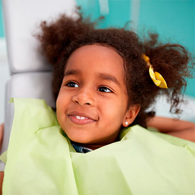 A pediatric dental patient sits in an exam chair