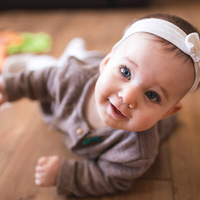 A baby laying on the floor and smiling