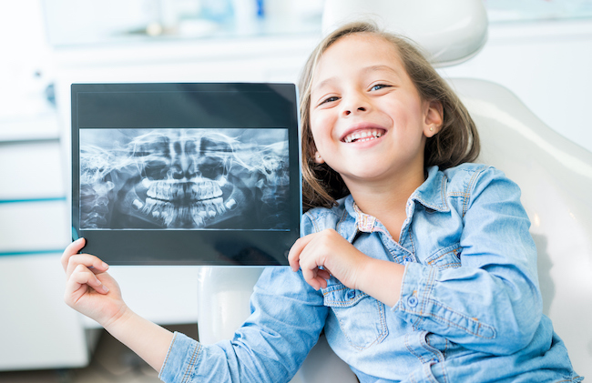 Girl at the dentist holding an x-ray