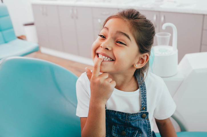 smiling child pointing at teeth