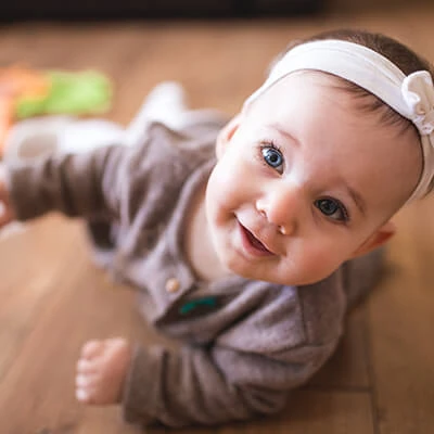 Infant smiling and crawling on the floor.